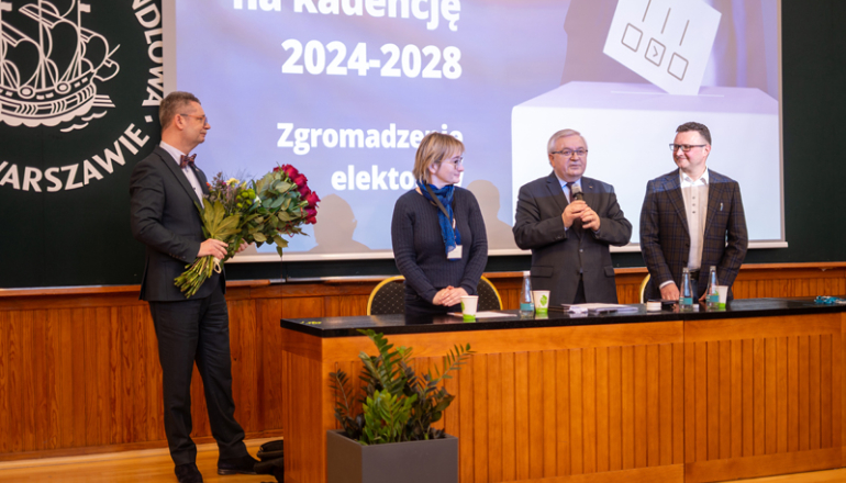 na zdjęciu komisja wyborcza oraz nowo wybrany rektor z kwiatami