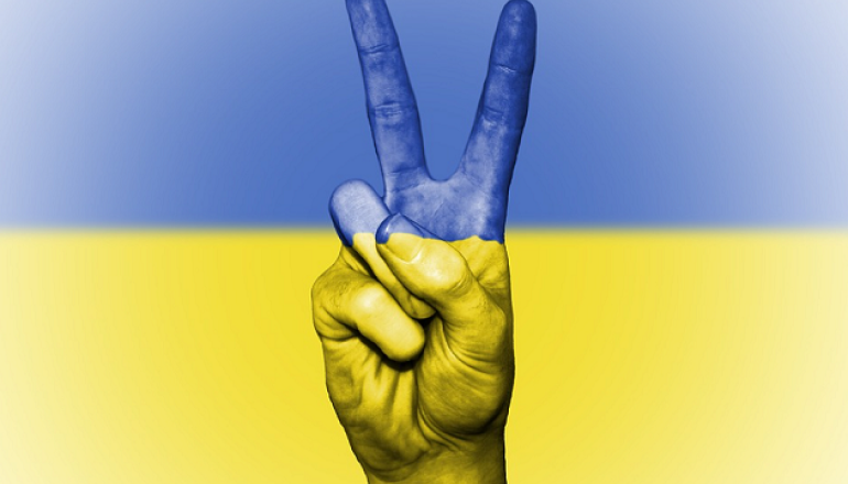 znak wiktorii wykonywany dłonią wpisany we flagę Ukrainy