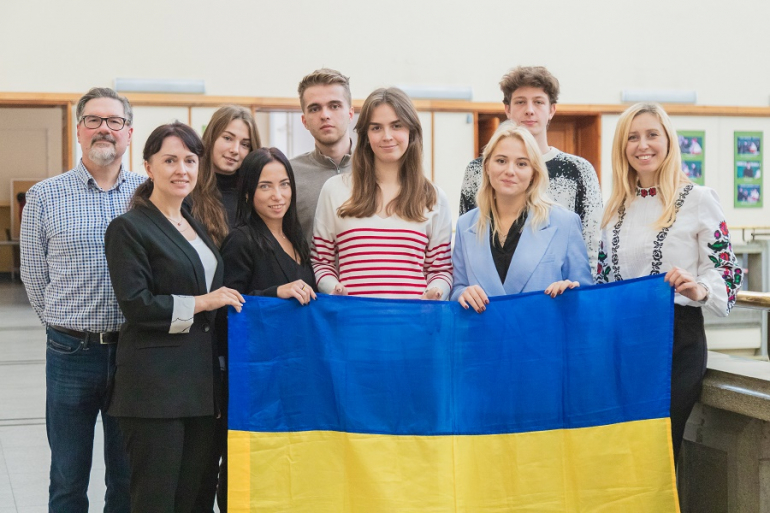 grupka osób w hall trzyma przed sobą ukraińską flagę
