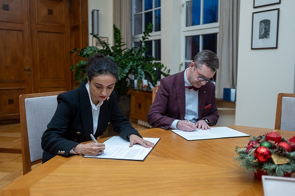 dwoje ludzi podpisuje dokumenty, siedząc za stołem