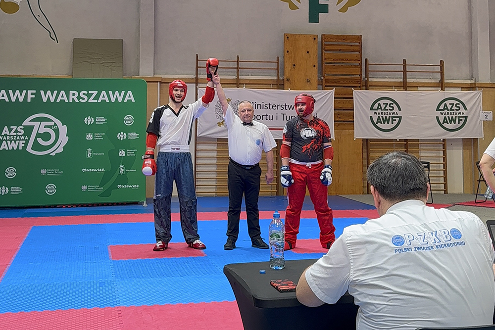 na zdjęciu werdykt, trzech mężczyzn, sędzia s podniesioną ręka zwycięzcy