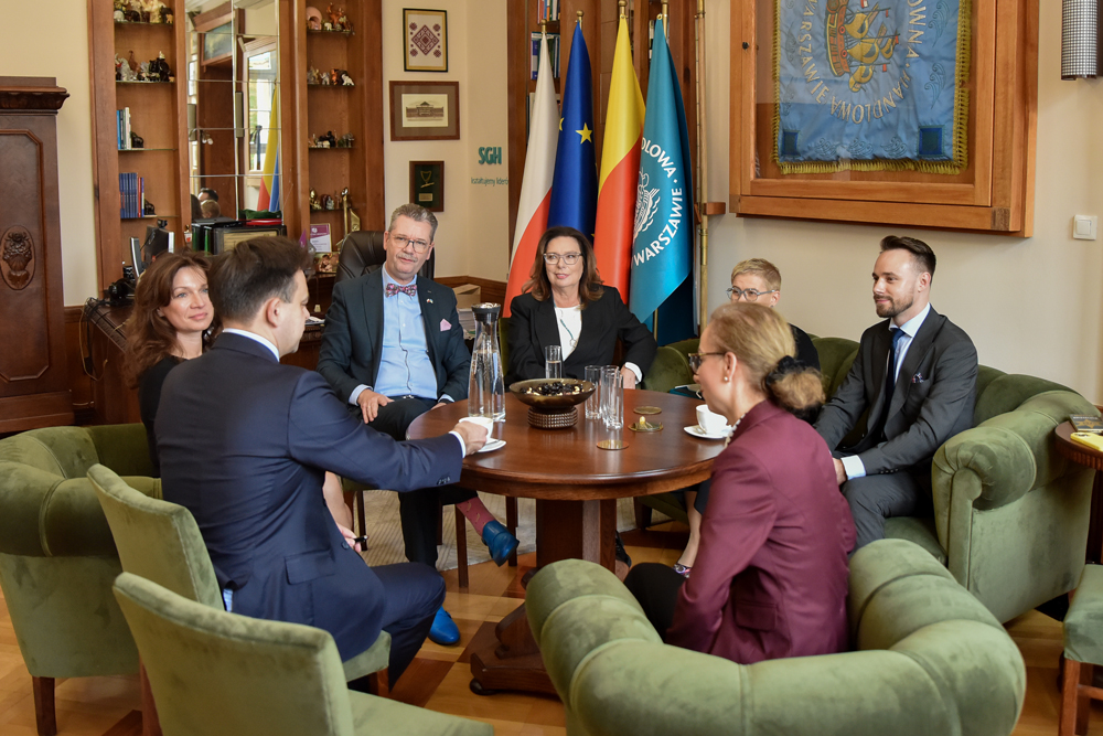 Grupa osób siedząca przy okrągłym stole w  gabinecie rektora SGH. Fot. Piotr Potapowicz