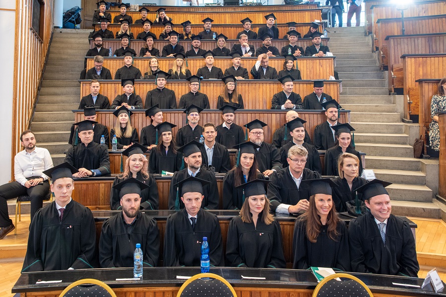 grupa absolwentów studiów MBA siedzi na auli; wszyscy mają na sobie togi i birety