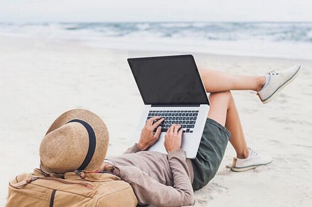 zdjęcie osoby na plaży z laptopem