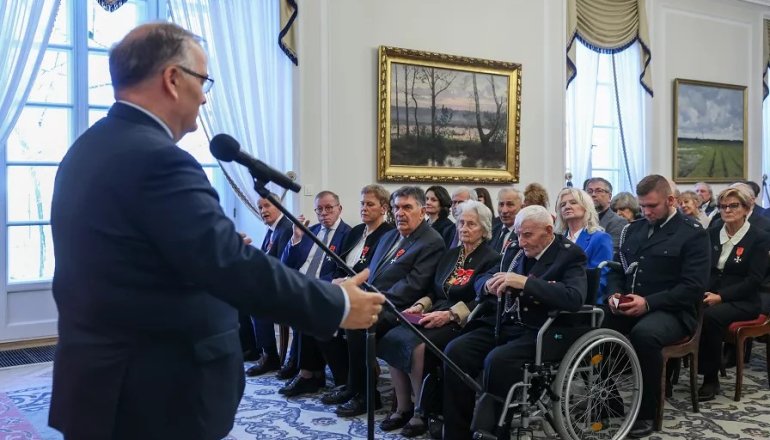 na zdjęciu mężczyzna przemawiający do osób siedzących w sali 