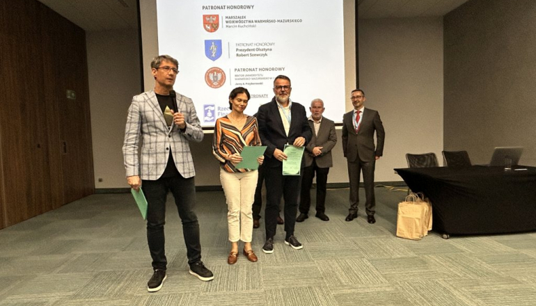 laureaci konkursu pozują do zdjęcia; w tle duży ekran 