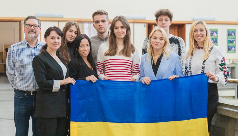 grupka osób w hall trzyma przed sobą ukraińską flagę