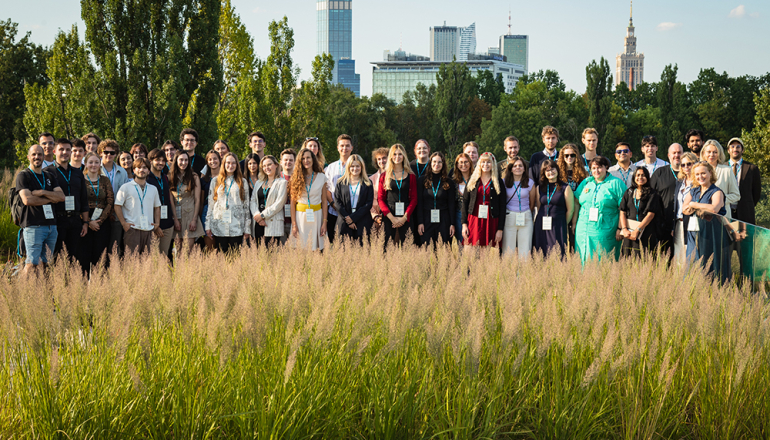grupa pozujących osób na tle centrum Warszawy