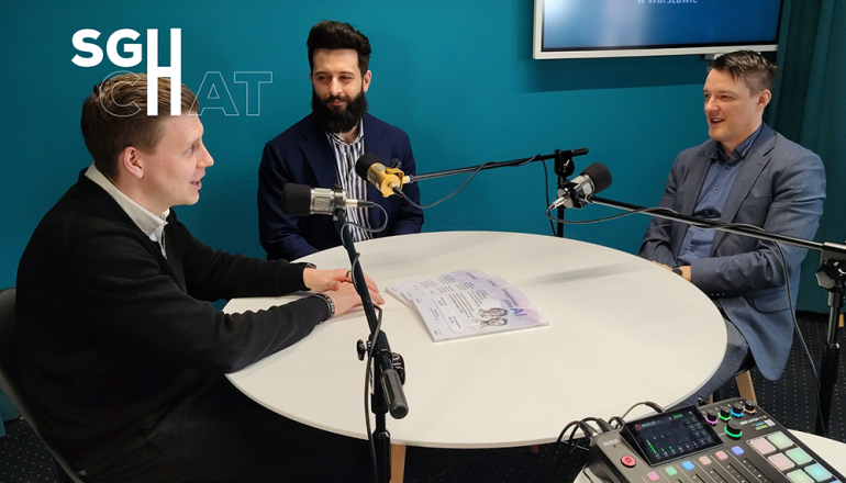 trzech panów siedzących przy stole z mikrofonami