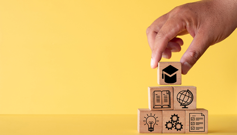 na żółtym tle dłoń układająca klocki z symbolami