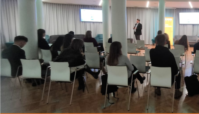 zdjęcie grupy osób na sali na dole pomarańczowy pasek z logami