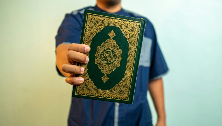 mężczyzna trzymający w ręku Koran