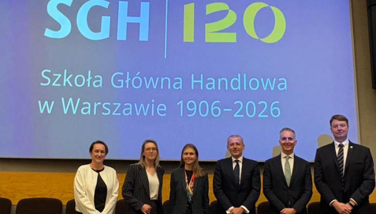 kilka osób podczas konferencji stoi za katedrą i pozuje doz zdjęcia