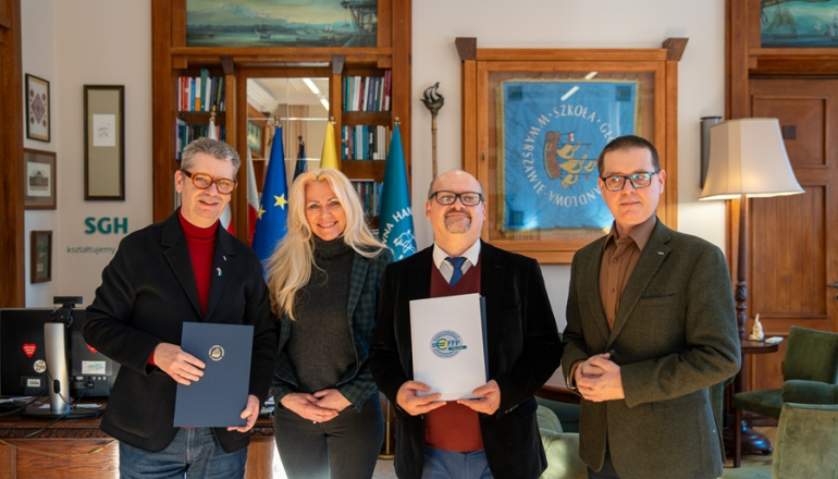 trzech mężczyzn i kobieta pozują do zdjęcia w gabinecie po podpisaniu porozumienia