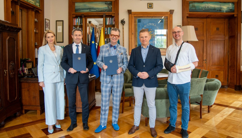 Kilka osób pozuje do zdjęcia w gabinecie po podpisaniu porozumienia