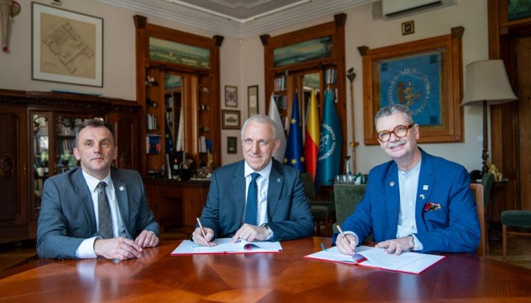 trzech mężczyzn siedzi przy stole po podpisaniu umowy