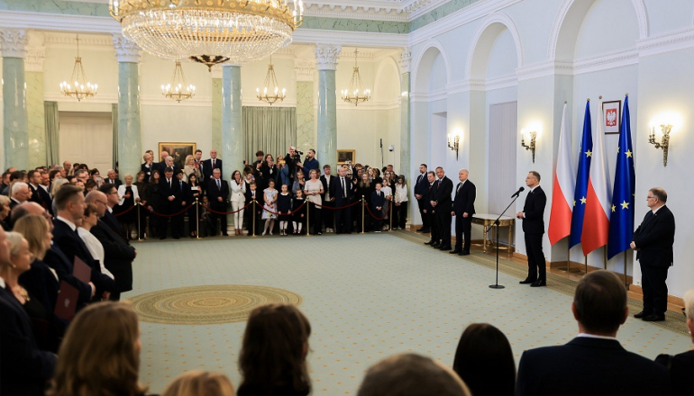 kilkadziesiąt osób na uroczystości u prezydenta; środek pomieszczenia pusty; zgromadzeni stoją przy ścianach