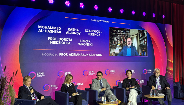 kilka osób siedzi na scenie podczas panelu