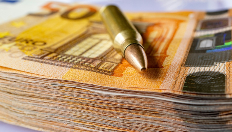 zdjęcie naboju/ łuski po naboju na stosie banknotów