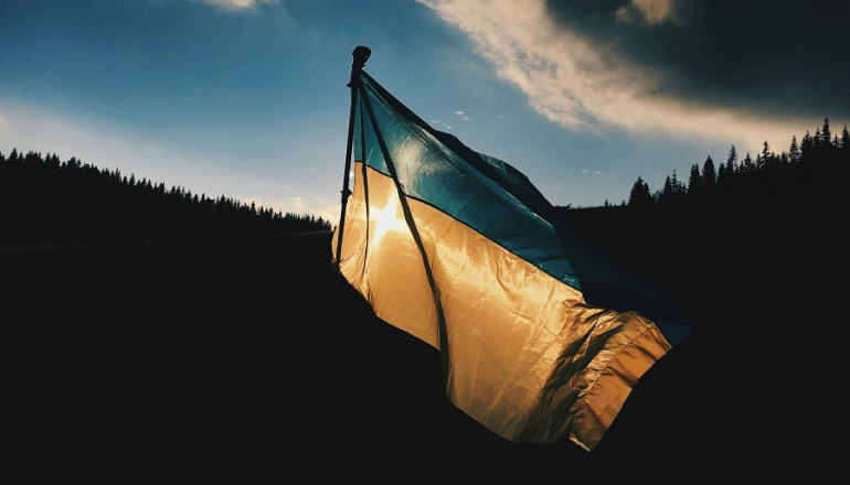 flaga Ukrainy na tle zachodzącego słońca w lesie