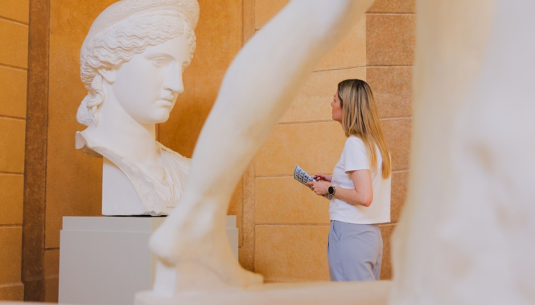 kobieta patrzy na antyczną rzeźbę w muzeum
