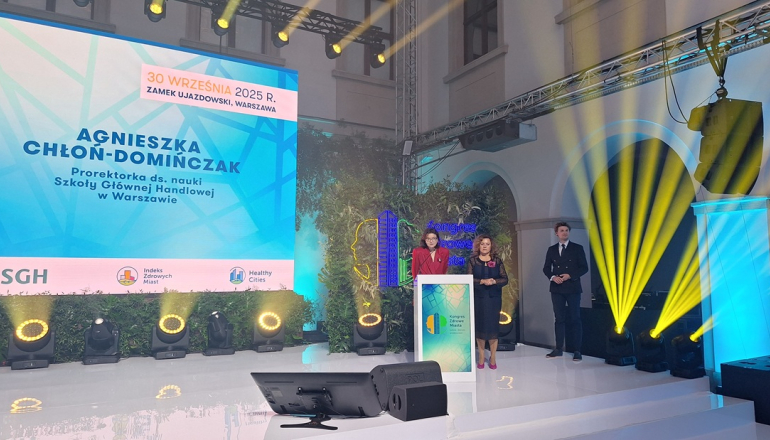 trzy osoby stoją na scenie, kobieta przemawia