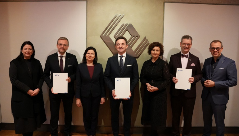kilka osób pozuje do zdjęcia; trzy z nich trzymają podpisane dokumenty