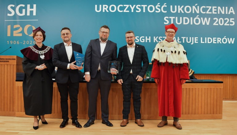 trzech mężczyzn w garniturach oraz kobieta i mężczyzna w togach rektorskich stoją na scenie