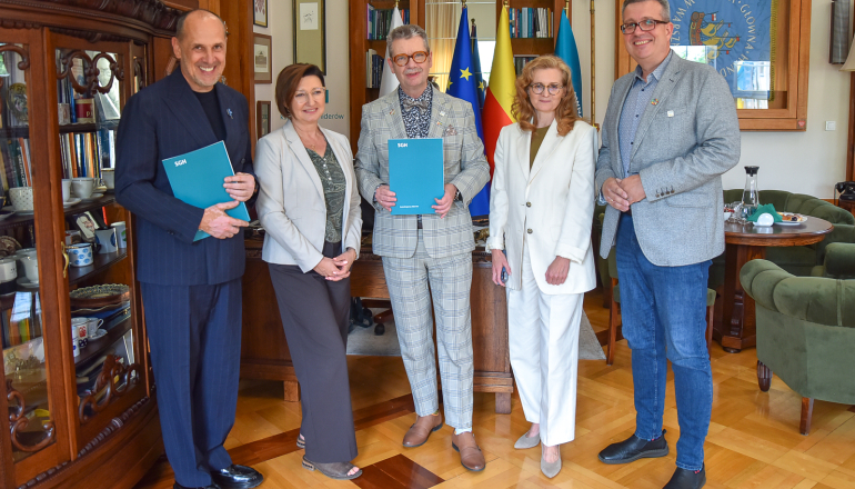 kilka osób pozuje do zdjęcia w gabinecie po podpisaniu porozumienia