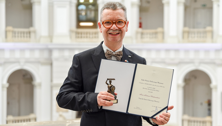 rektor SGH na tle krużganków na PW trzyma dyplom i statuetkę