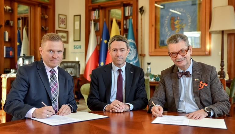 trzech mężczyzn podpisuje dokumenty