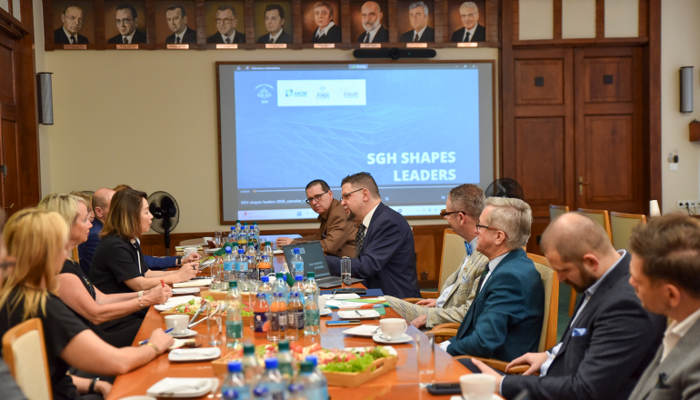 kilkanaście osób rozmawia przy stole konferencyjnym, w tle wyświetlana prezentacja