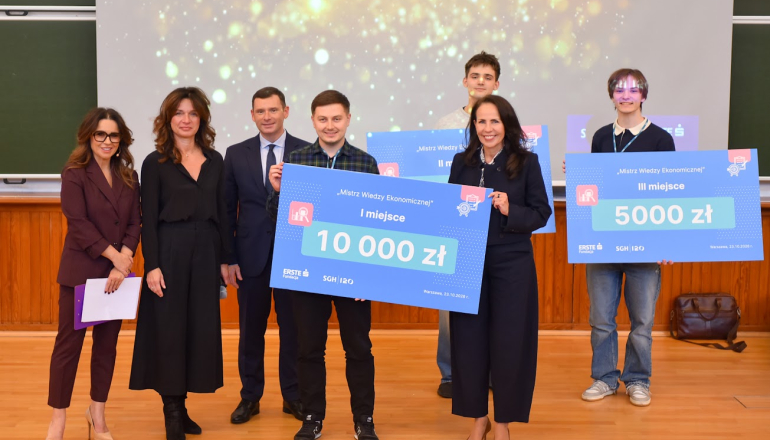 kilka osób na scenie z symbolicznymi czekami wygranymi w konkursie