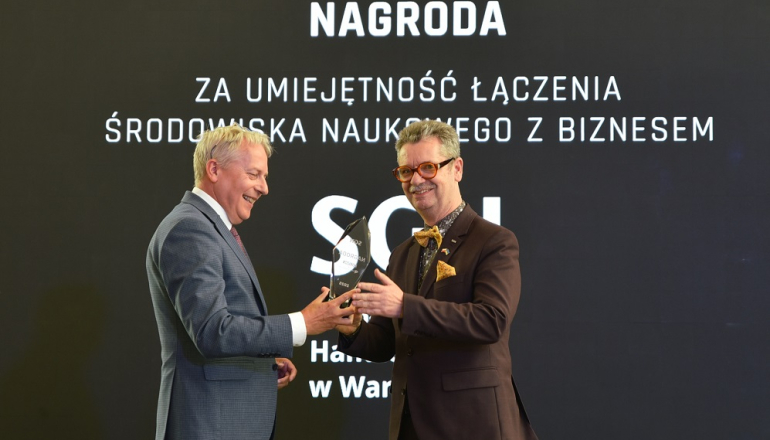 jeden mężczyzna przekazuje drugiemu statuetkę na gali