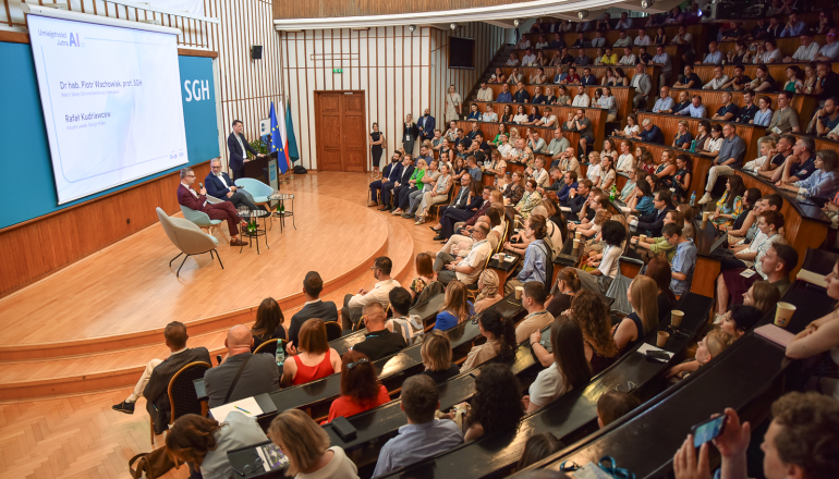 aula uczelniana wypełniona tłumem gości, na scenie rozmawia dwóch mężczyzn