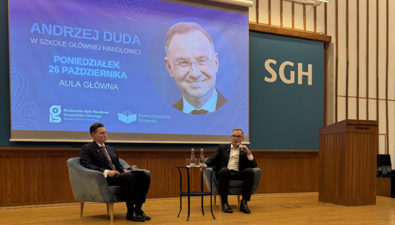 dwóch mężczyzn rozmawia ze sobą na scenie, z tyłu wyświetlony ekran