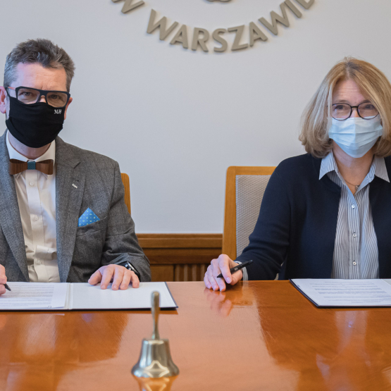 Rektor Piotr Wachowiak i dyrektor Maria Andrzejewska podpisują umowę o współpracę. Znajdują się w sali senatu. 