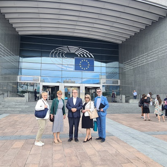 grupka osób stoi przed budynkiem Parlamentu Europejskiego