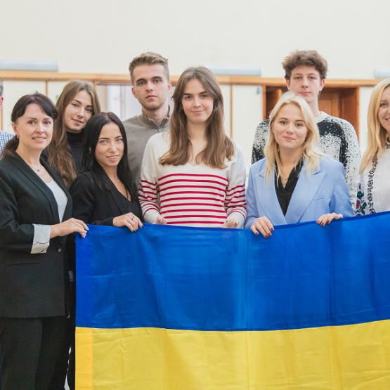 grupka osób w hall trzyma przed sobą ukraińską flagę