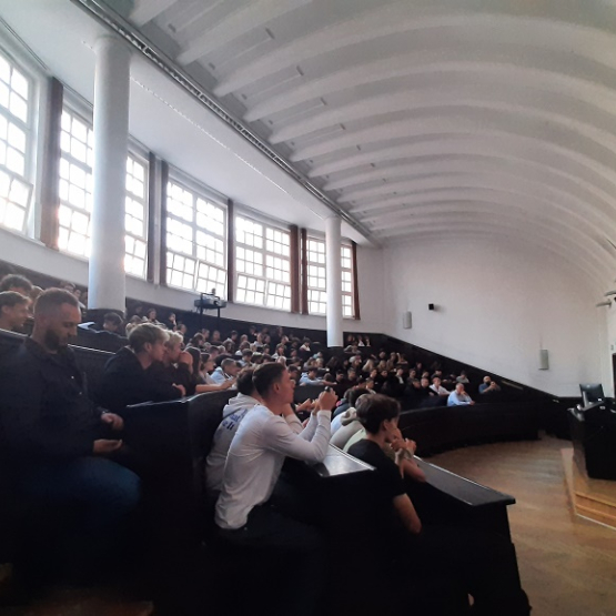 aula na uczelni wypełniona uczniami szkół srednich, na katedrze wykładowca