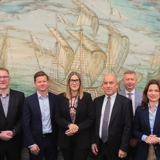 grupa osób pozuje do zdjęcia na tle fresku statku handlowego