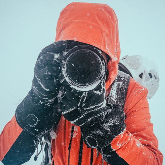 mężczyzna w czerwonej kurtce z aparatem fotograficznym