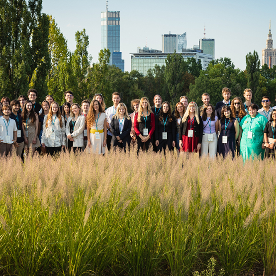 grupa pozujących osób na tle centrum Warszawy