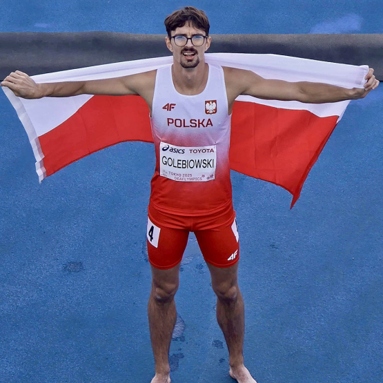 mężczyzna na bieżni z rozpostartą flagą Polski na plecach