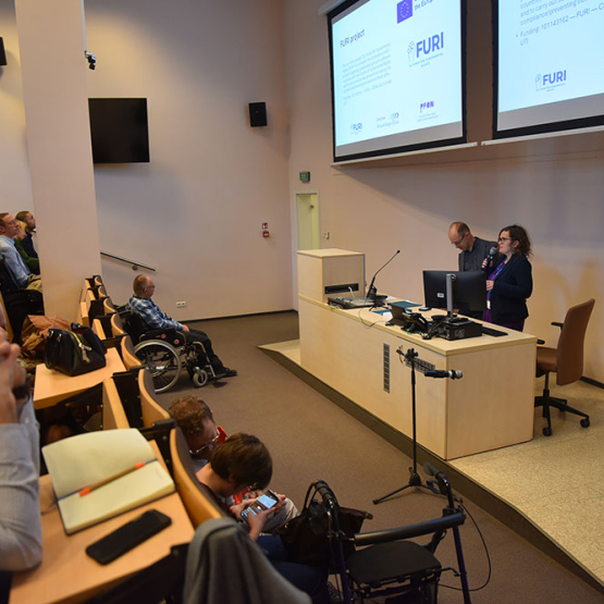Na zdjęciu aula z publicznością i prowadzący za katedrą
