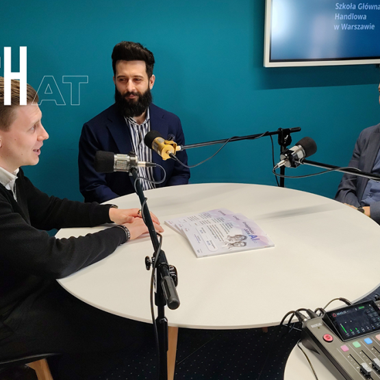 trzech panów siedzących przy stole z mikrofonami