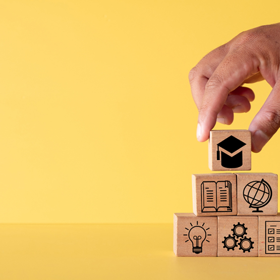 na żółtym tle dłoń układająca klocki z symbolami