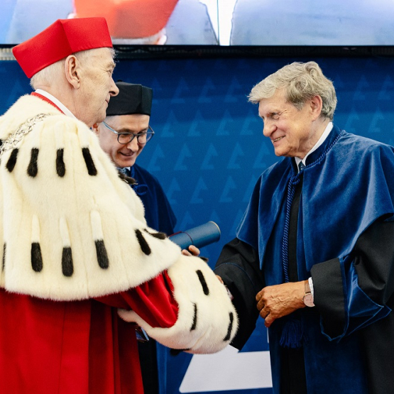 dwóch mężczyzn w togach; jeden w todze rektorskiej składa gratulacje drugiemu w todze doktora honoris causa