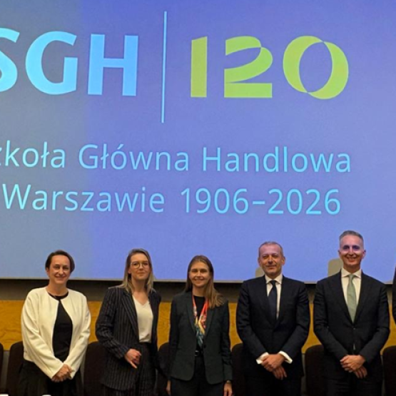 kilka osób podczas konferencji stoi za katedrą i pozuje doz zdjęcia