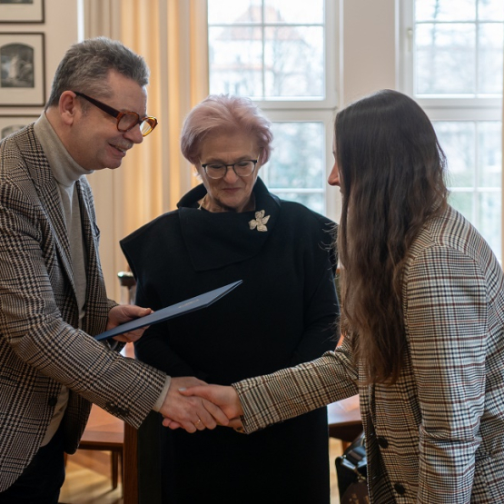 mężczyzna składa gratulacje młodej kobiecie, po środku druga kobieta